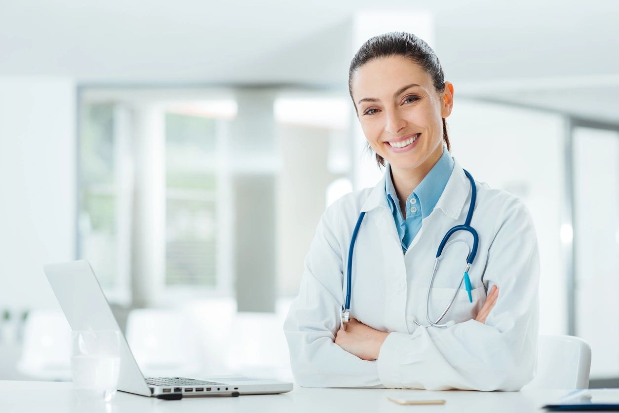 A female doctor sitting at the table with her arms crossed.