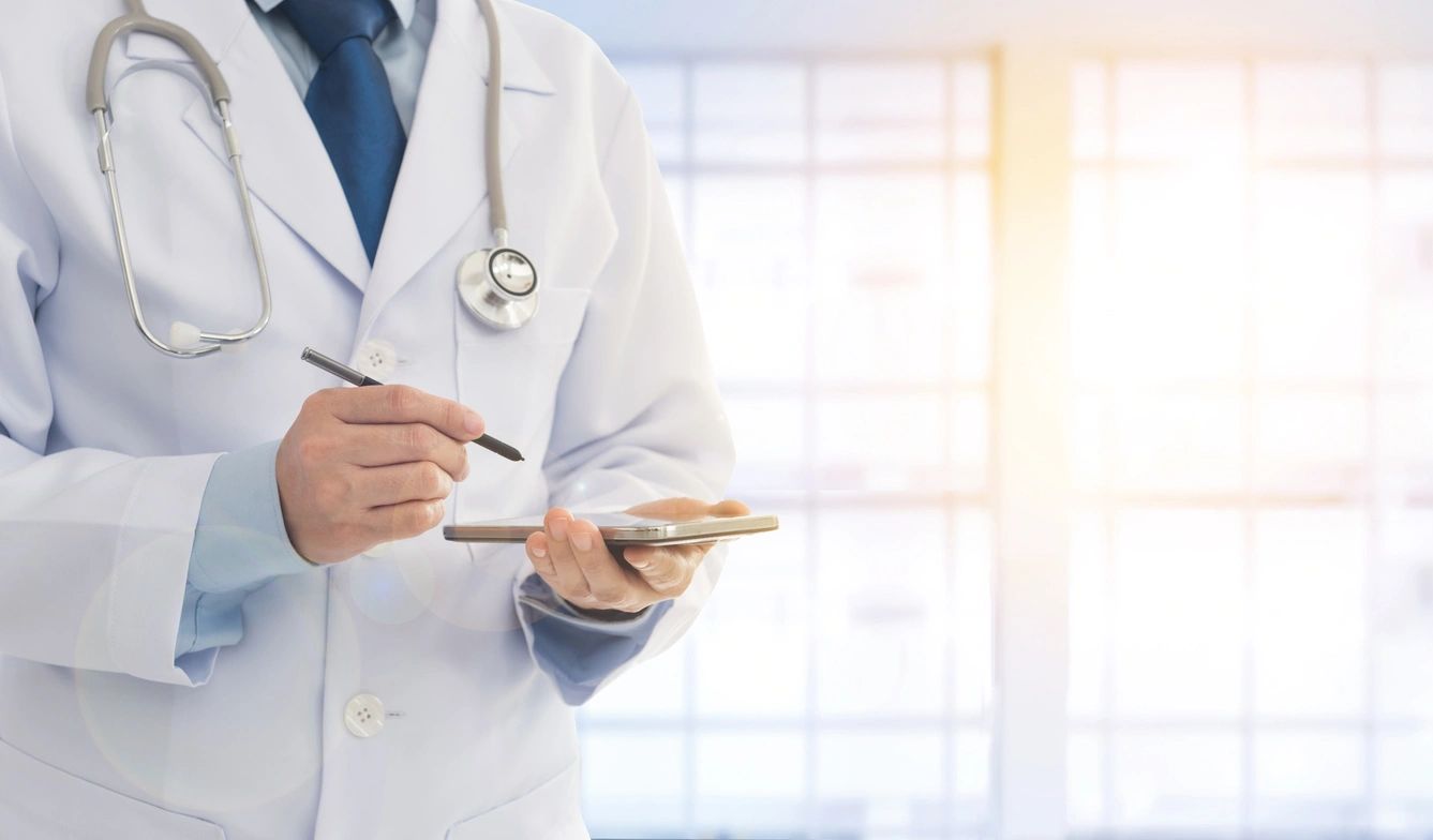 A doctor holding two pens and a cell phone.