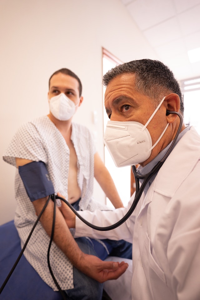 Two doctors are wearing masks and one is holding a stethoscope.