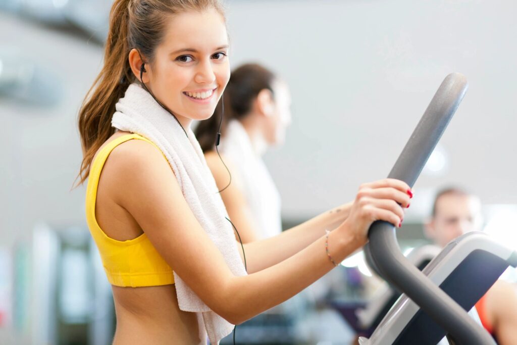 A woman is smiling while riding an exercise bike.