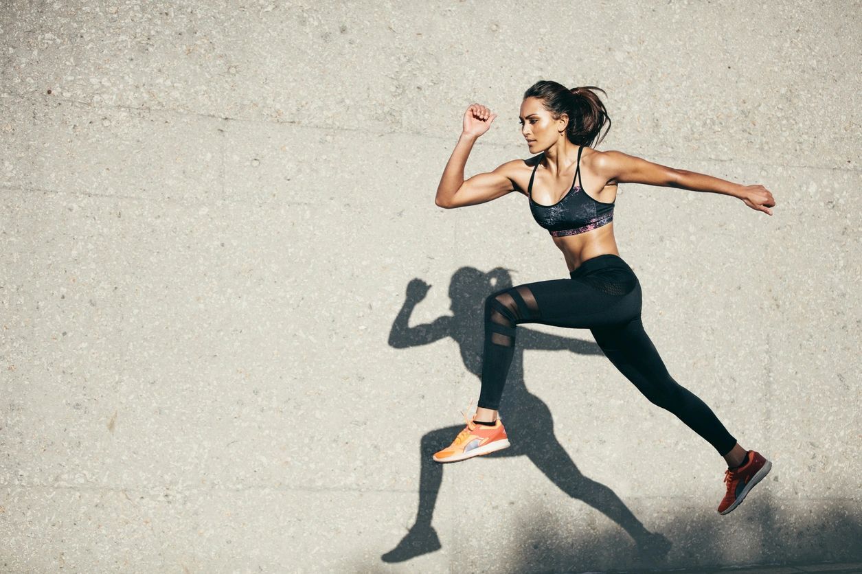 A woman running on the pavement in a black outfit